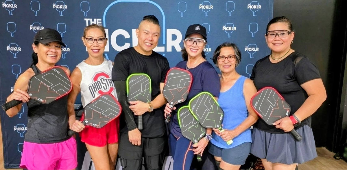 Six players at a pickleball club holding CPX Hyper+ paddles in Red and Green